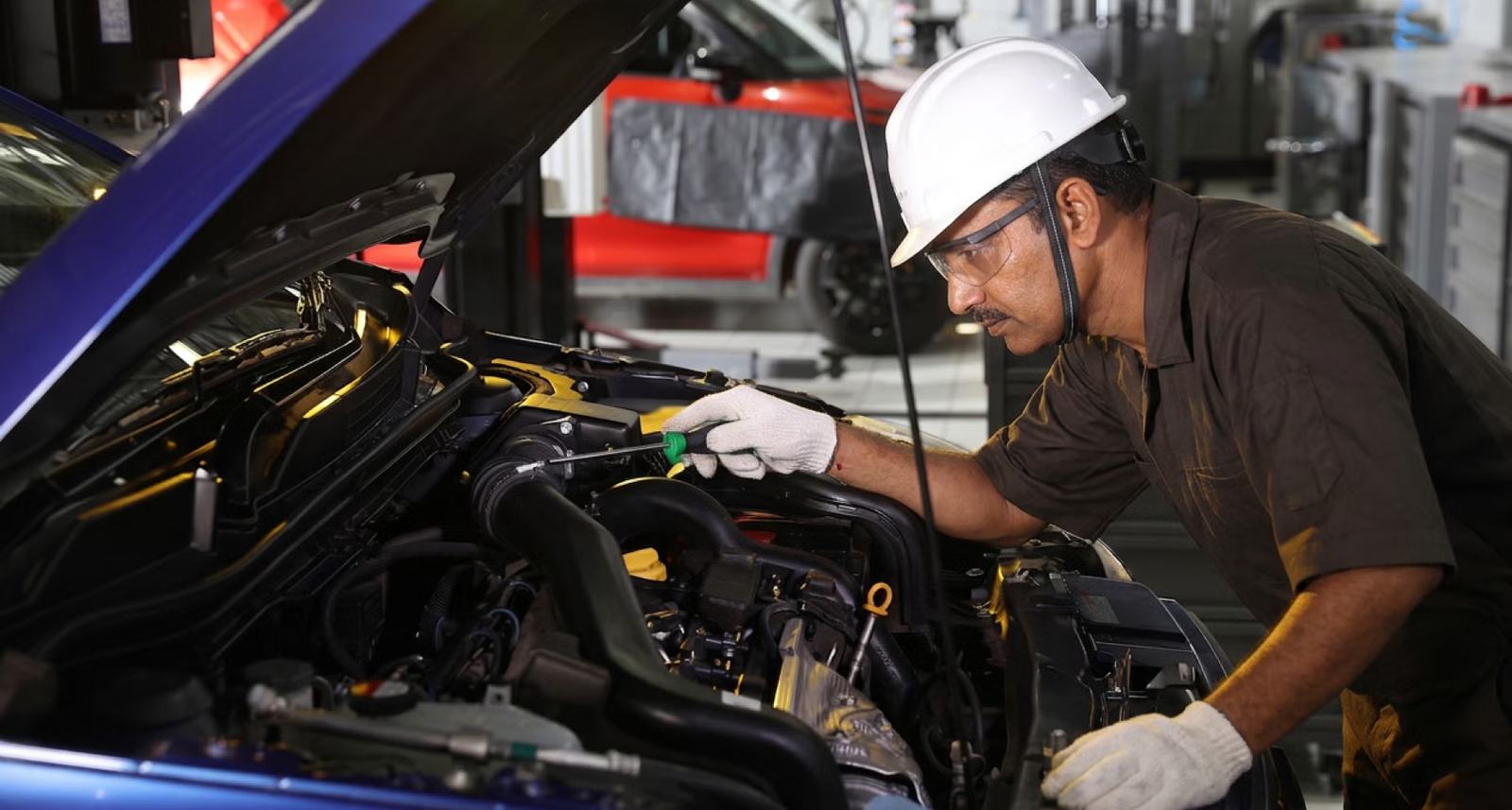 A Maruti-trained technician working under the bonnet