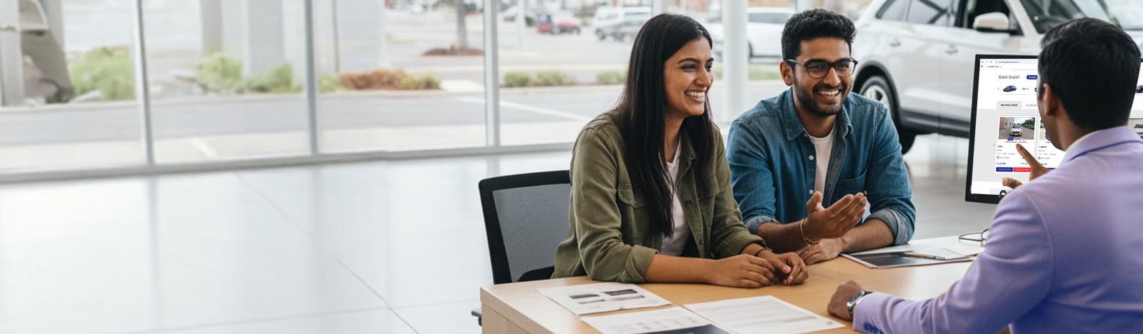A sales advisor going through paperwork with two customers