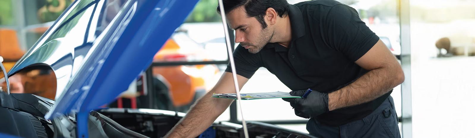 A technician inspecting the engine bay of a used car