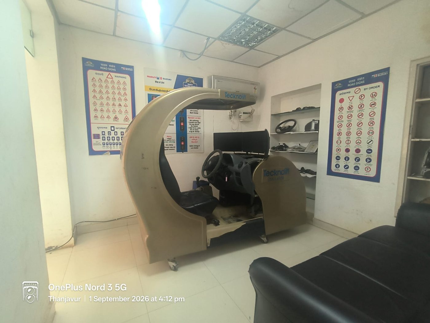 Driving simulator with steering wheel, pedals and display screen in the training room