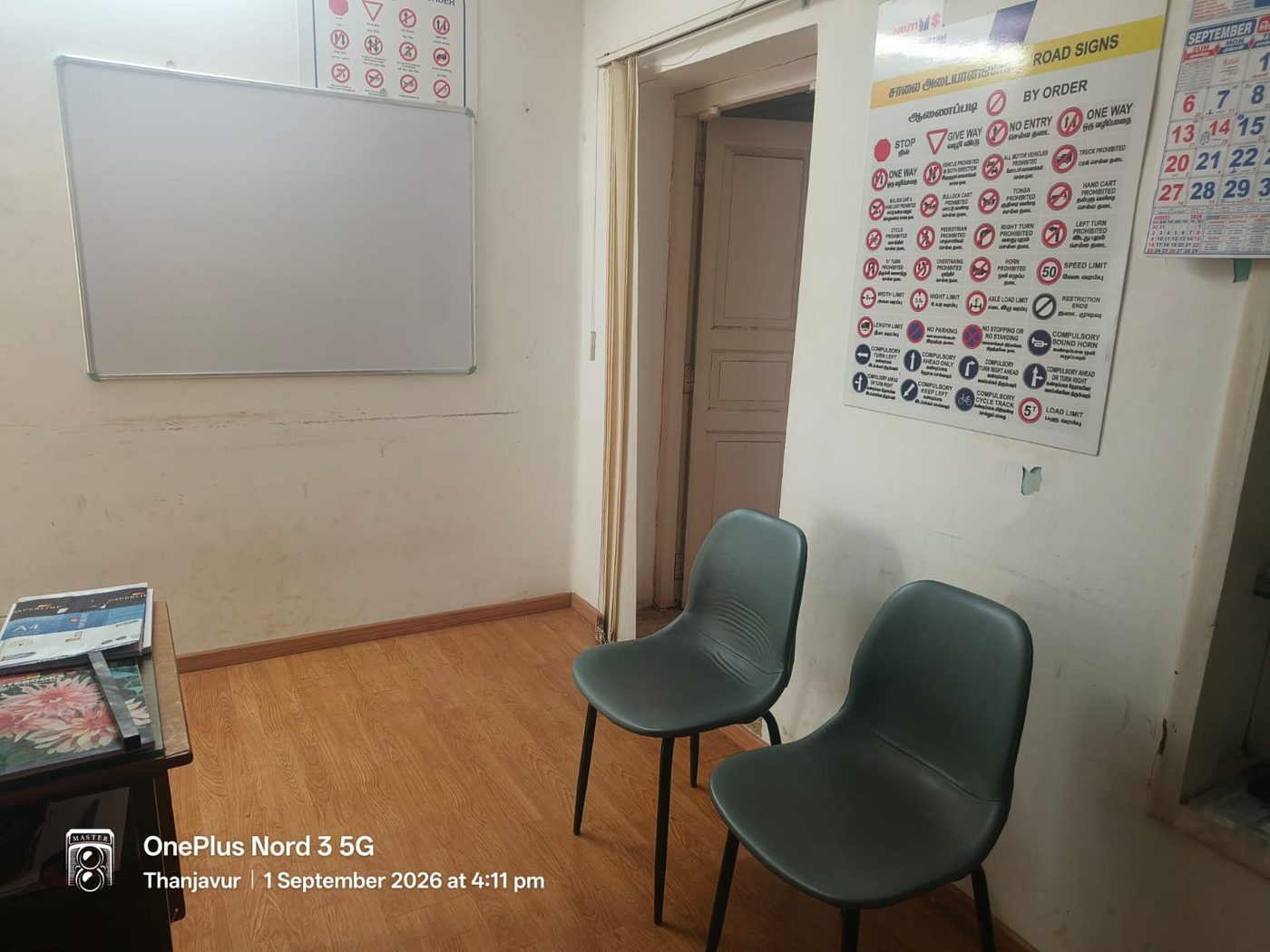 Theory classroom with a whiteboard and bilingual road sign charts on the wall